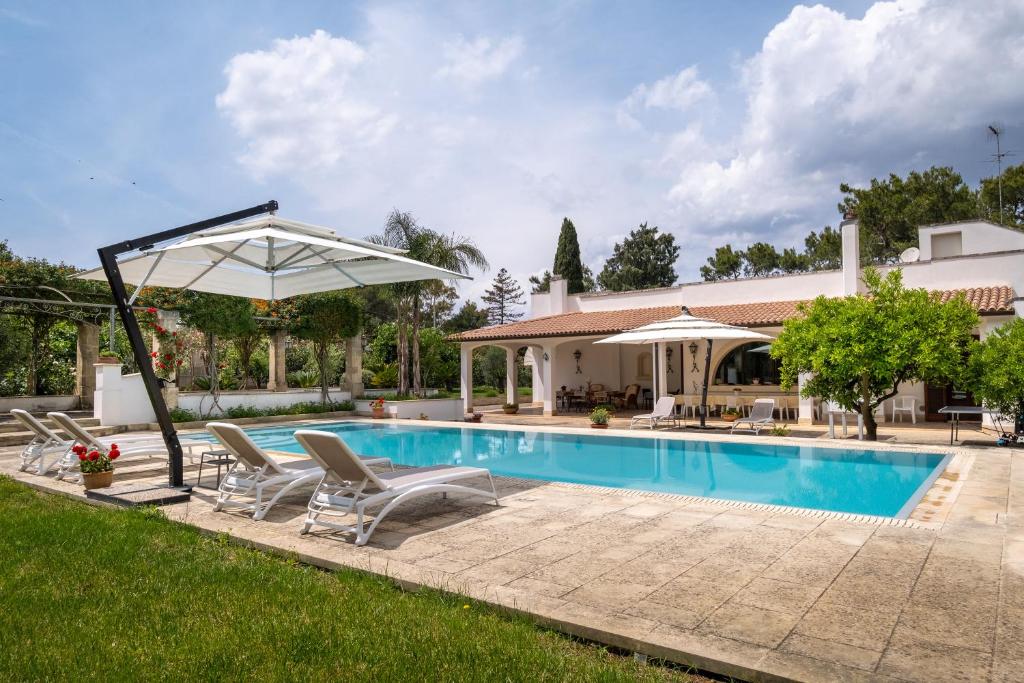 a pool with chairs and an umbrella next to a house at Il Carrettino in Monteroni di Lecce