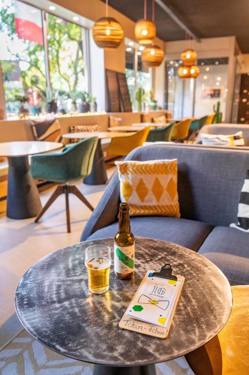 a bottle of beer sitting on a table with a drink at ibis Styles Paris 16 Boulogne in Paris