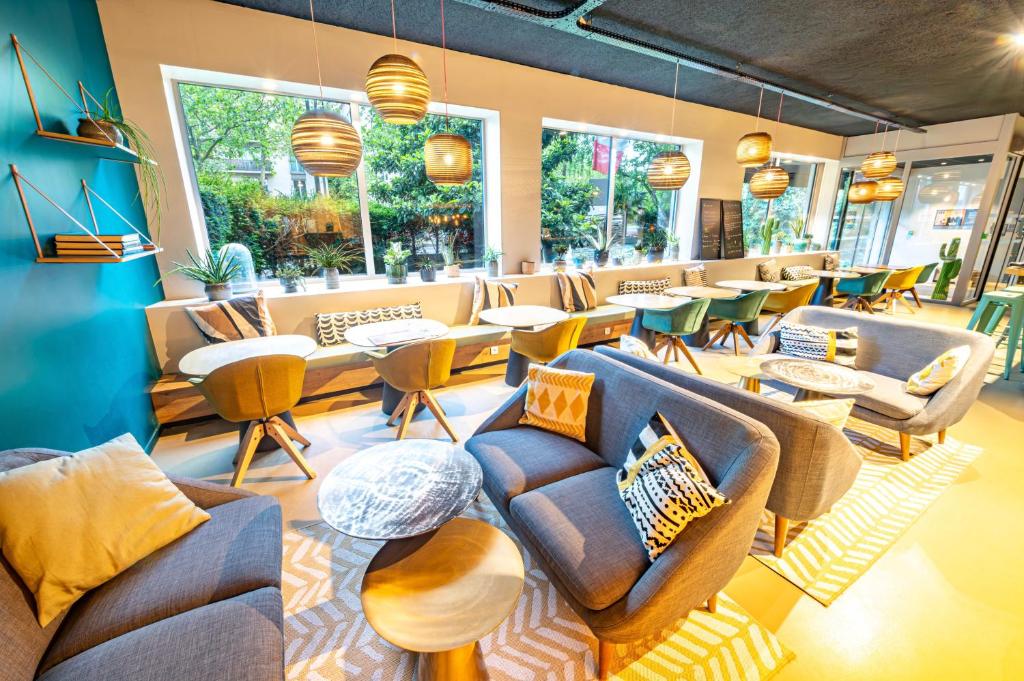 a waiting room with couches and tables and windows at ibis Styles Paris 16 Boulogne in Paris