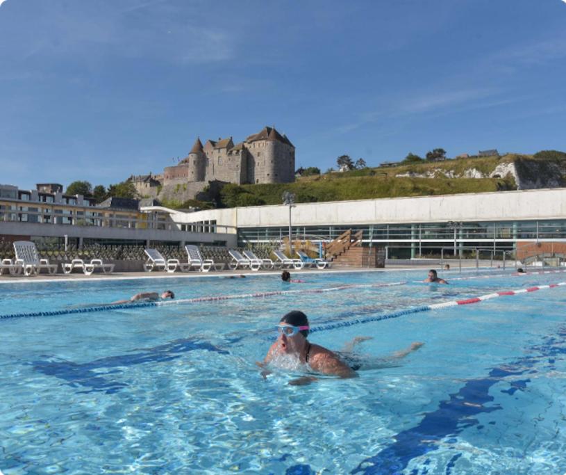 eine Person, die in einem Schwimmbad mit einem Schloss im Hintergrund schwimmt in der Unterkunft Hotel particulier 200m2 plein centre et plage - 2 à 25 personnes in Dieppe