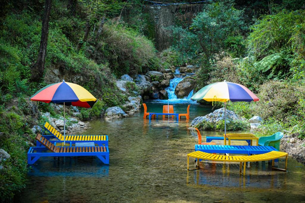 a group of chairs and umbrellas in a river at The Hosteller Mussoorie By the Streamside, Kempty in Mussoorie