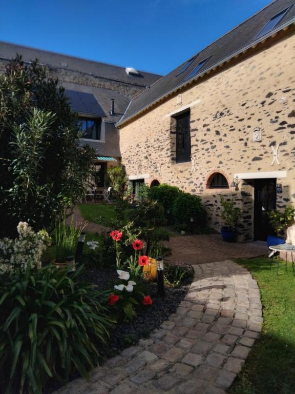 ein Steinhaus mit einem Garten und einem Gehweg in der Unterkunft Le domaine de Bachmay in Laval