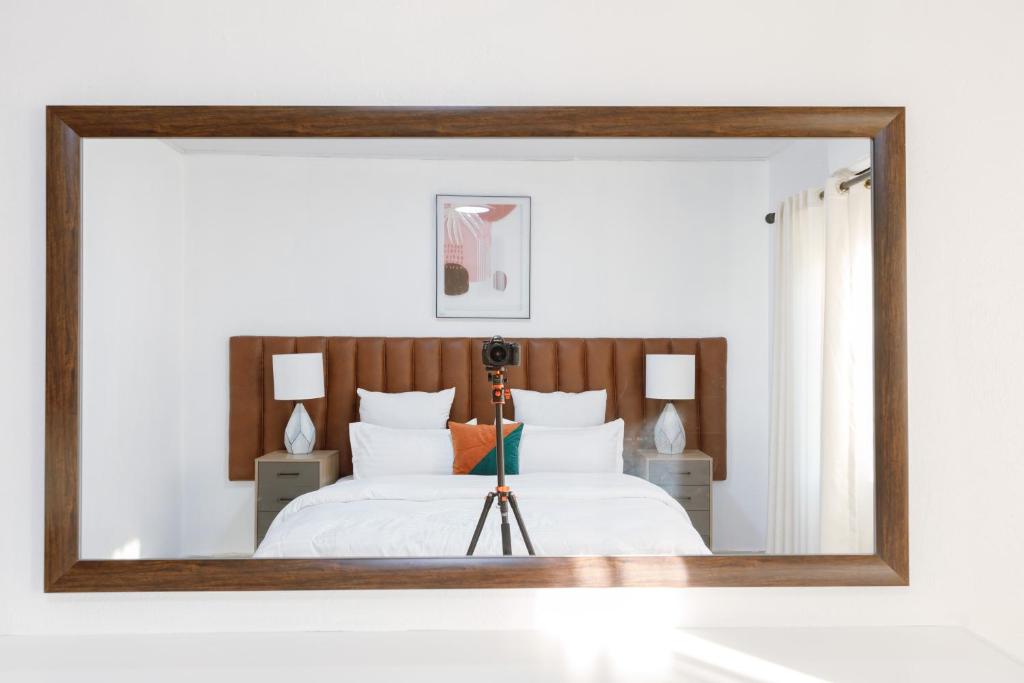 a mirror reflecting a bed with a camera on a tripod at Epignosis Apartments in Lusaka