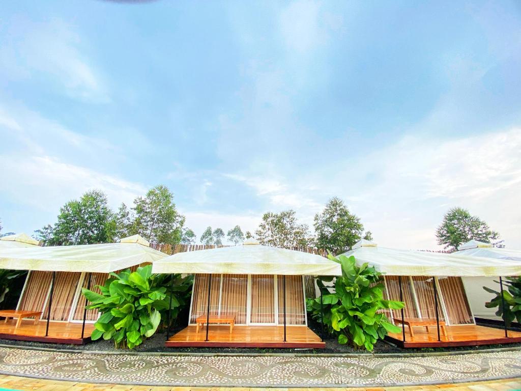 a row of buildings with tables and umbrellas at Buana Glamping in Pengalengan