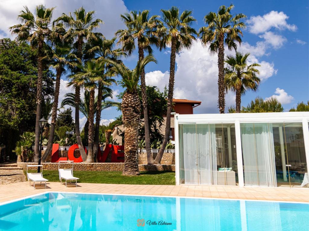 una villa con piscina e palme di B&B Villa Adriana ad Andria