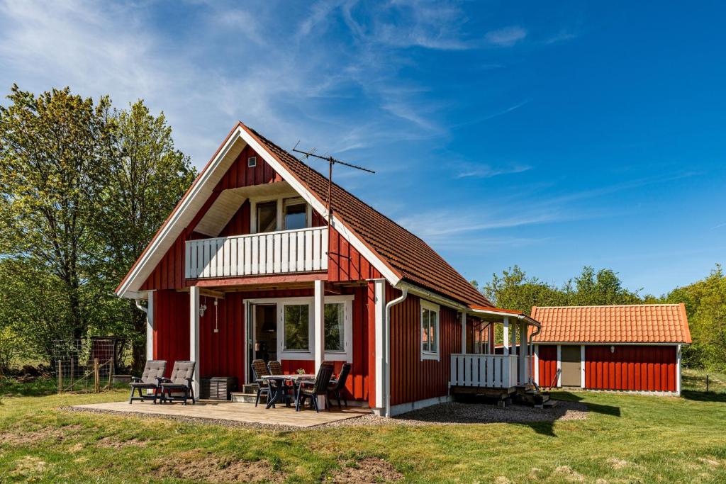 uma casa vermelha com um alpendre e um pátio em Holiday accommodation with great nature experience near Laholm em Knäred