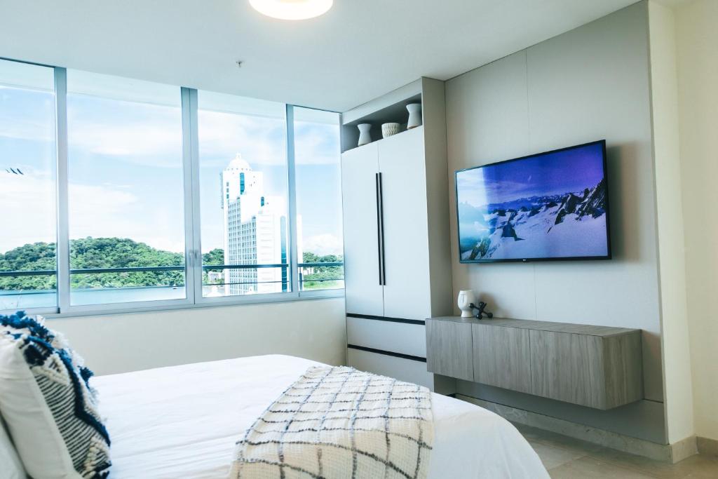 1 dormitorio con TV en la pared y ventanas en Oceanview Apt Near Panama City w/ King Bed & More, en Playa Bonita Village