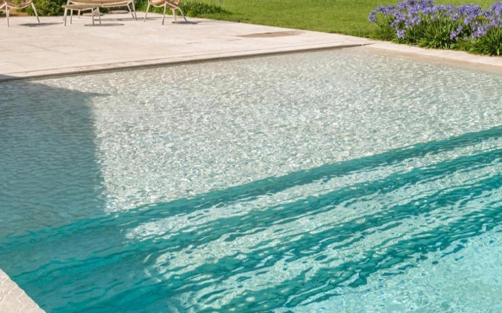 una piscina di acqua blu con sedie e fiori viola di Stefania a San Lorenzo