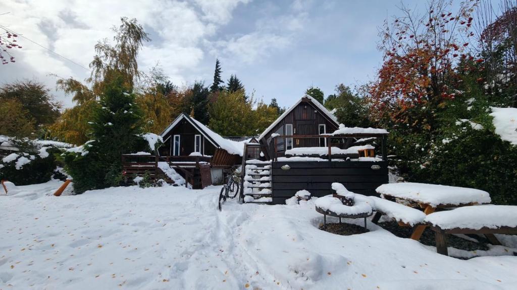 una casa con nieve en el suelo delante de ella en Alaska Patagonia Hostel en San Carlos de Bariloche