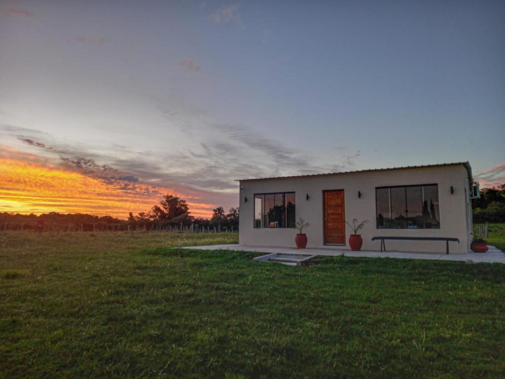 a small white building in a field with a sunset at El Lirio in Artigas