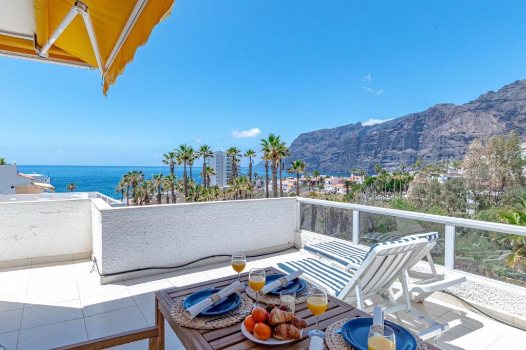 Cliff View Terrace by Dream Homes Tenerife في بويرتو دي سانتياغو: طاولة وكراسي على شرفة مطلة على المحيط