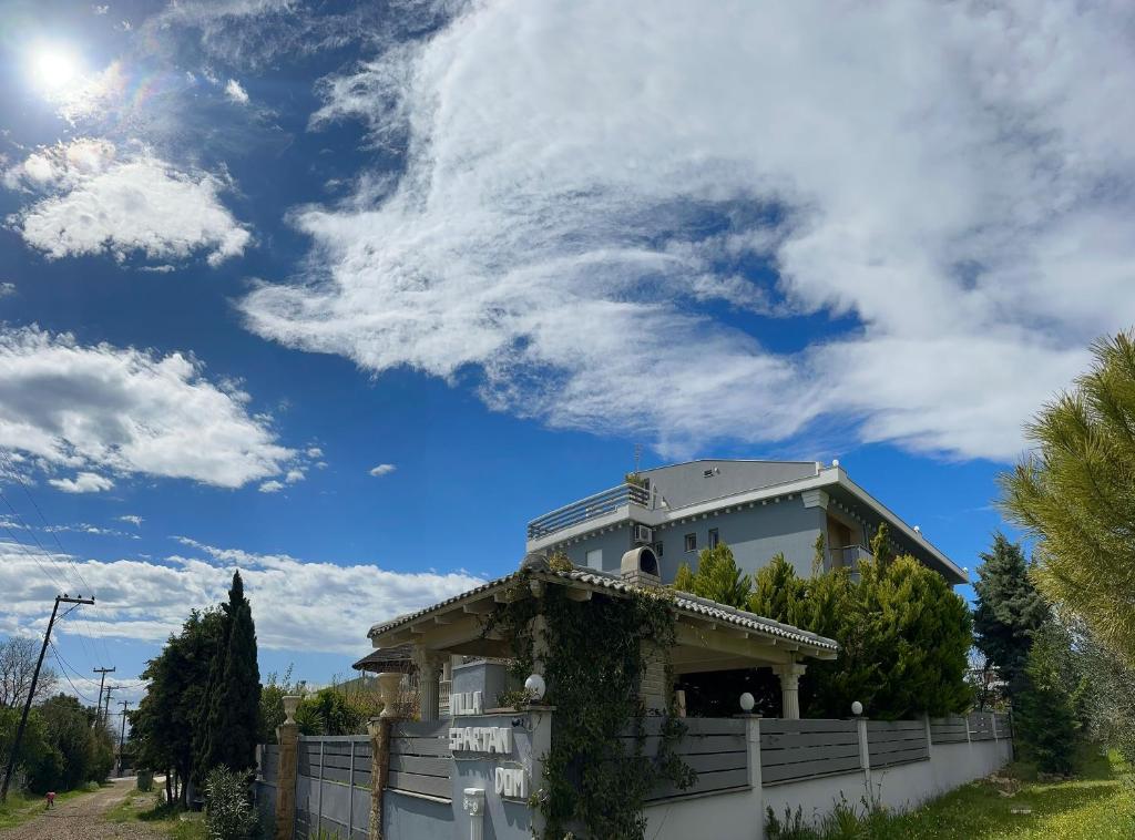 ein Haus mit einem weißen Zaun und einem blauen Himmel in der Unterkunft Villa Spartandom in Gerakini