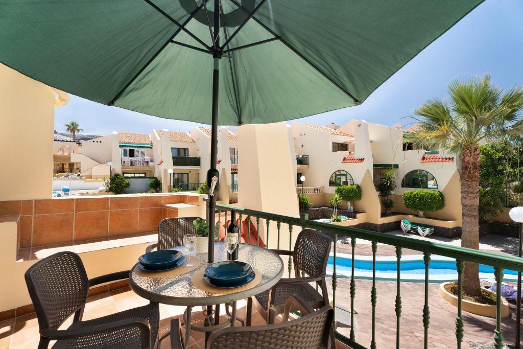 een patio met een tafel en stoelen en een parasol bij Mareverde K131 in Adeje