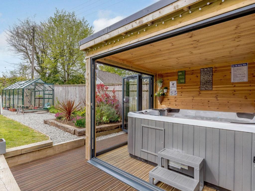a hot tub on a deck next to a garden at 5 Bed in Falmouth 65745 in Gwennap