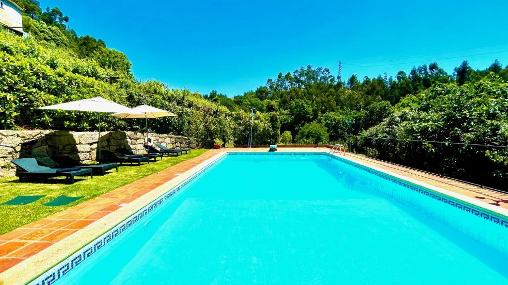 a swimming pool with two chairs and an umbrella at Villa Amarela in Penafiel