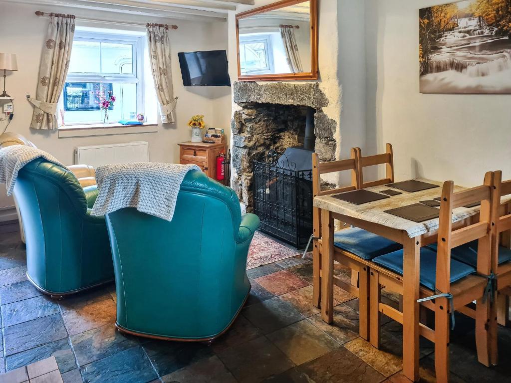 a living room with a table and chairs and a fireplace at Castiel Cottage in Yspytty-Ifan