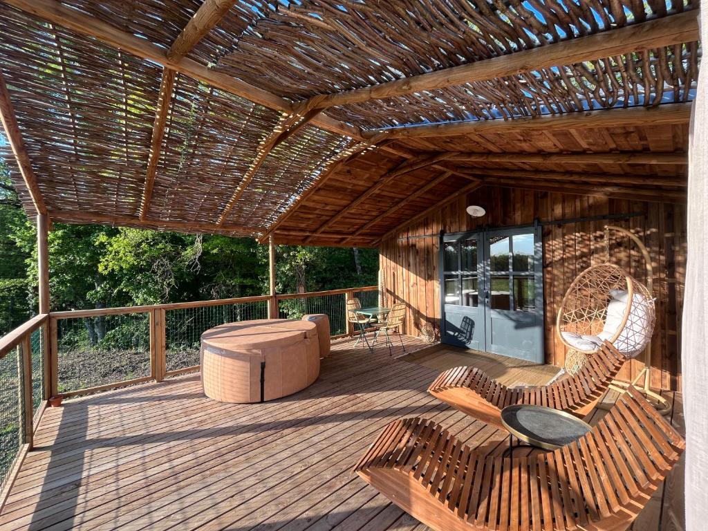 a deck with a pergola and chairs and a couch at Ushuaïa Villages La Buissonnière Lodges in Chisseaux