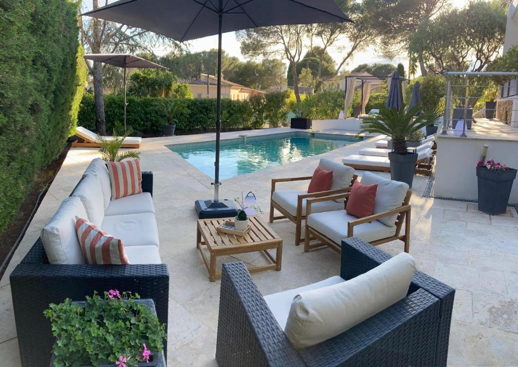 - une terrasse avec des chaises et un parasol à côté de la piscine dans l'établissement "LES ALIZES" Côté PISCINE PROCHE BORD DE MER, à Saint-Raphaël