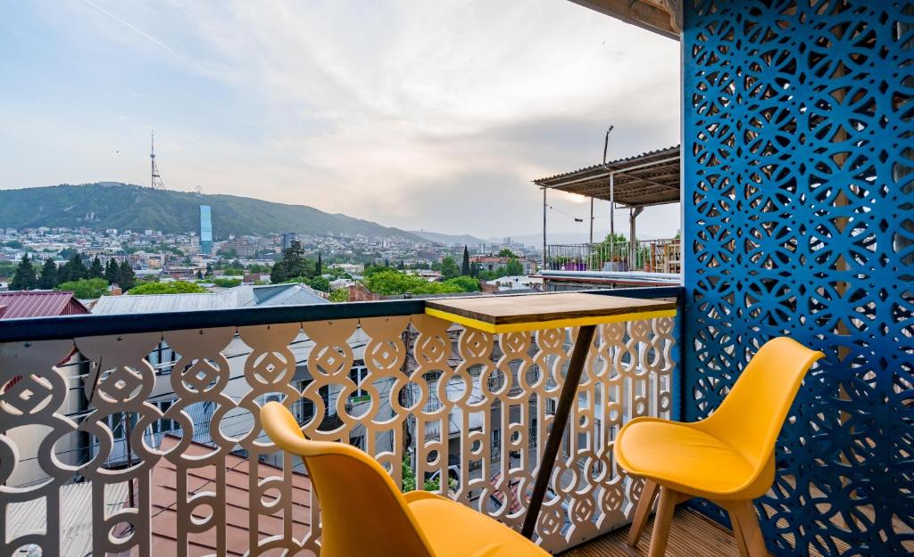 Un balcón con sillas amarillas y una mesa. en Apart View Hotel & Spa en Tiflis