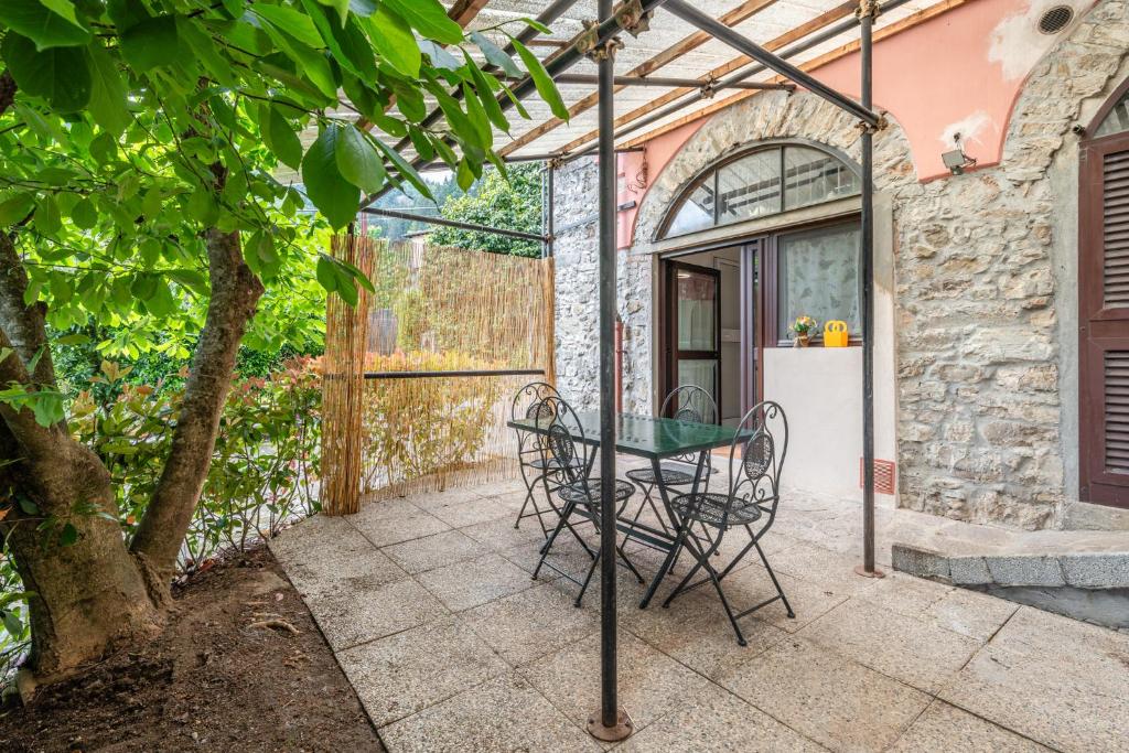 um pátio com uma mesa e cadeiras em frente a uma casa em Casa delle Rose em Borgo a Mozzano