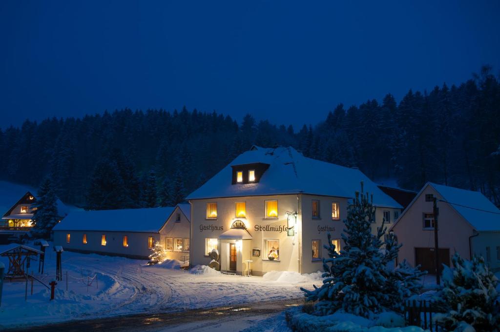 een groot gebouw in de sneeuw 's nachts bij Gasthaus Stollmühle in Stützengrün