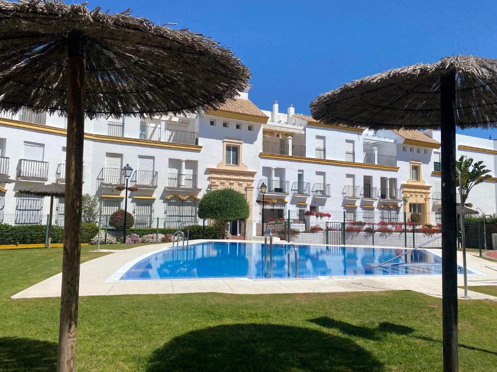 a large building with a swimming pool and two umbrellas at Apartamento a pie de playa in Rota