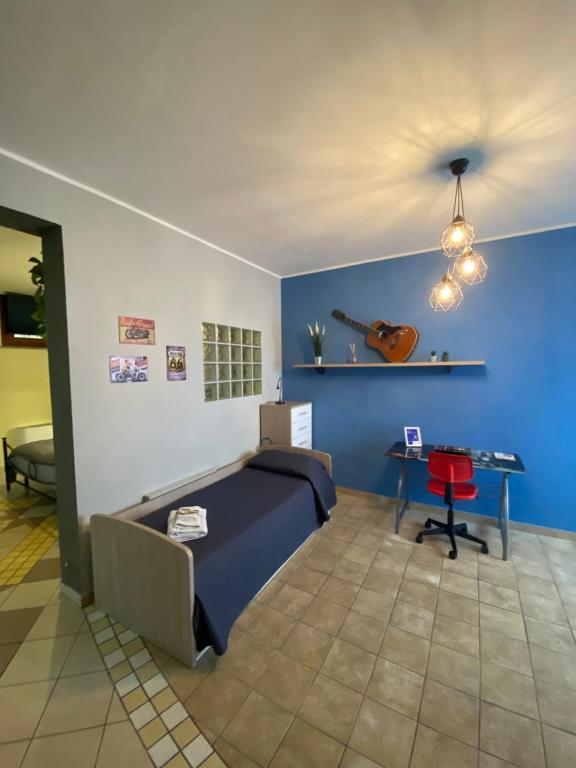 Habitación con cama y mesa con guitarra en la pared en Demetra Residence en Enna