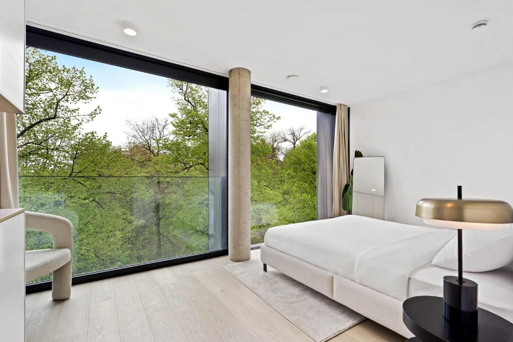 een slaapkamer met een wit bed en een groot raam bij Chic 80sqm Luxe Apt - Heart of Luxembourg City in Luxemburg