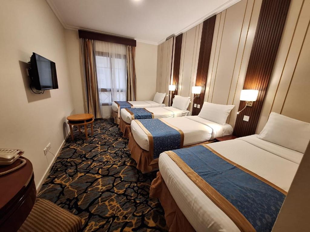 a hotel room with four beds and a television at فندق منار الإيمان in Medina