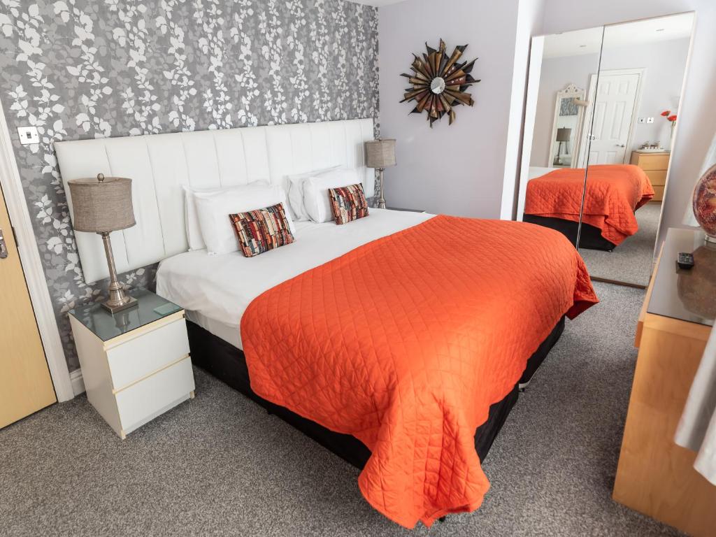 um quarto com uma cama grande e um cobertor laranja em The Kenley Hotel em Blackpool