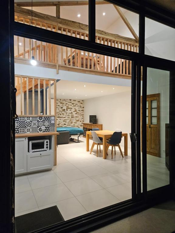 a kitchen and living room with a table and a dining room at La Petite Grange in Chavagnes-en-Paillers
