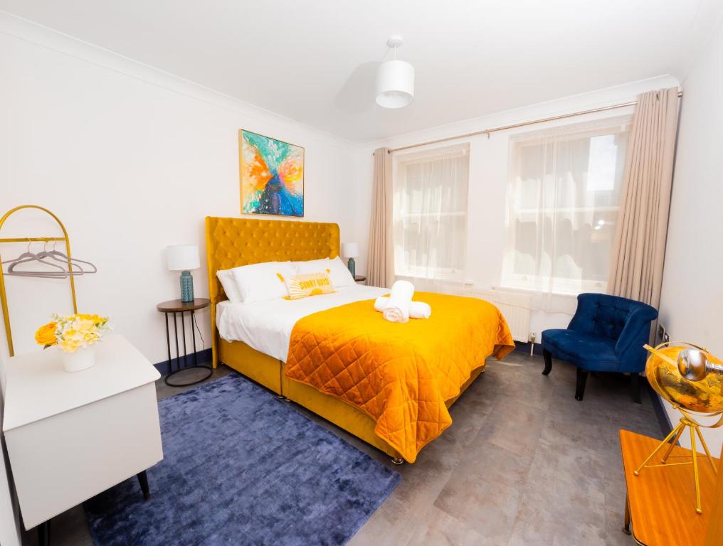 um quarto com uma cama amarela e uma cadeira azul em Ramsgate Boutique Apartment em Ramsgate