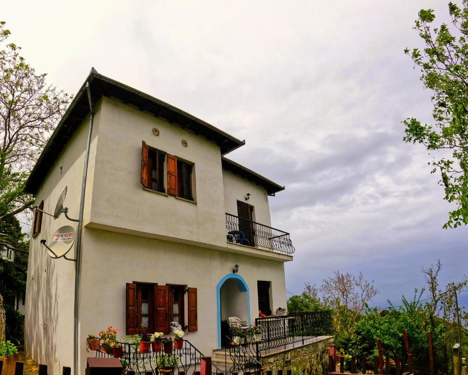 a white house with a balcony and people on it at Katafigio Home in Tsagkarada Village in Tsagarada