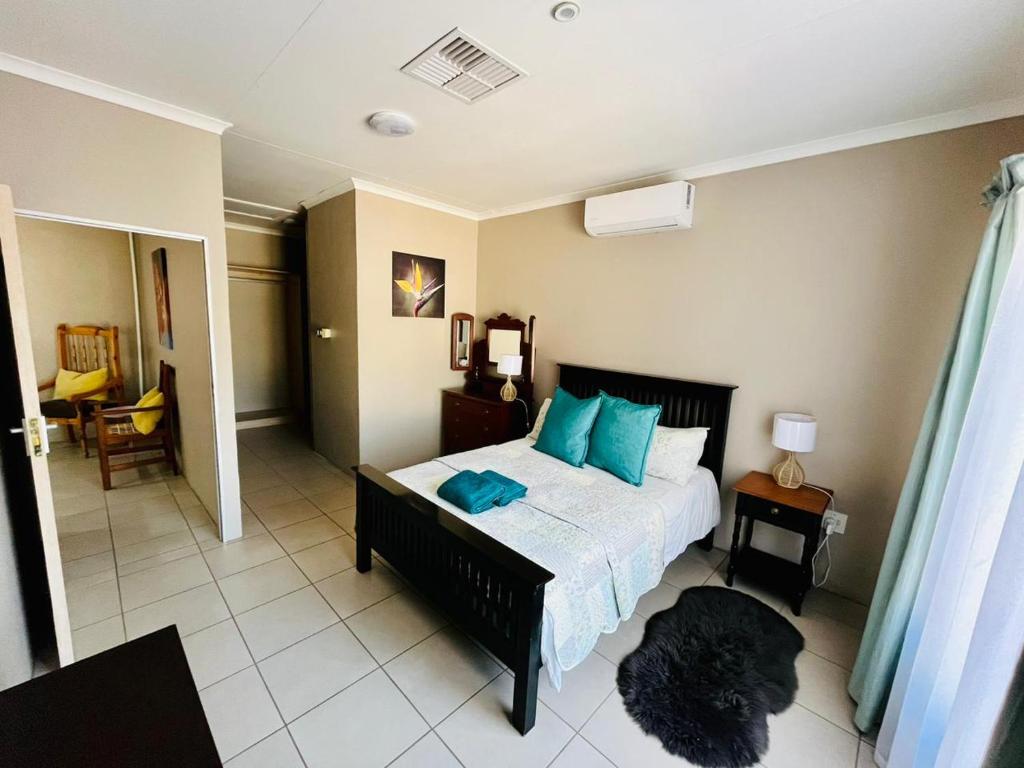1 dormitorio con 1 cama grande con almohadas azules en Ivanka's Self-Catering Flat en Kimberley