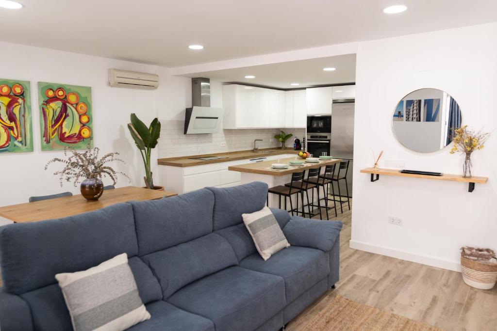 ein Wohnzimmer mit einem blauen Sofa und einer Küche in der Unterkunft Calvario 53 by 7Escalones in Rota