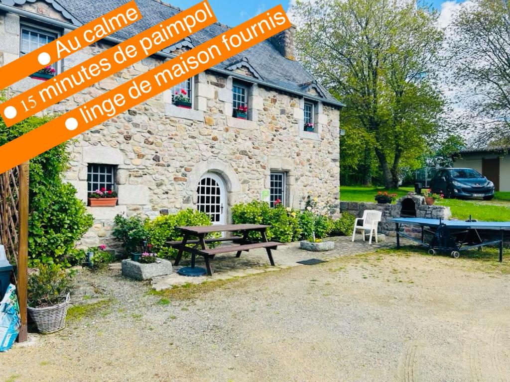 une maison en pierre avec une table de pique-nique devant elle dans l'établissement Maison traditionnelle bretonne proche de la mer, à Quemper-Guézennec