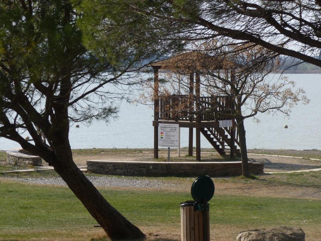 un parc avec une tour de sauvetage face à l'eau dans l'établissement Cottage du Lac, à Olonzac