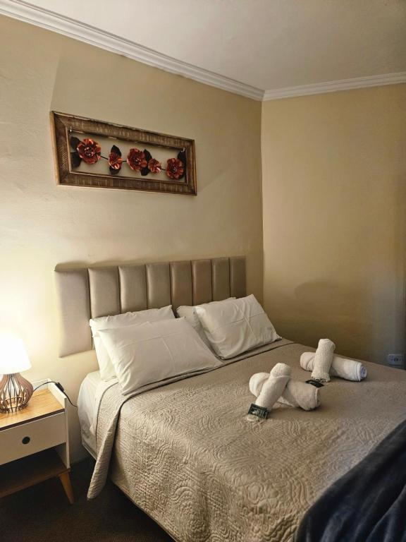 ein Schlafzimmer mit einem Bett mit zwei ausgestopften Tieren darauf in der Unterkunft Pousada Araucária in Campos do Jordão