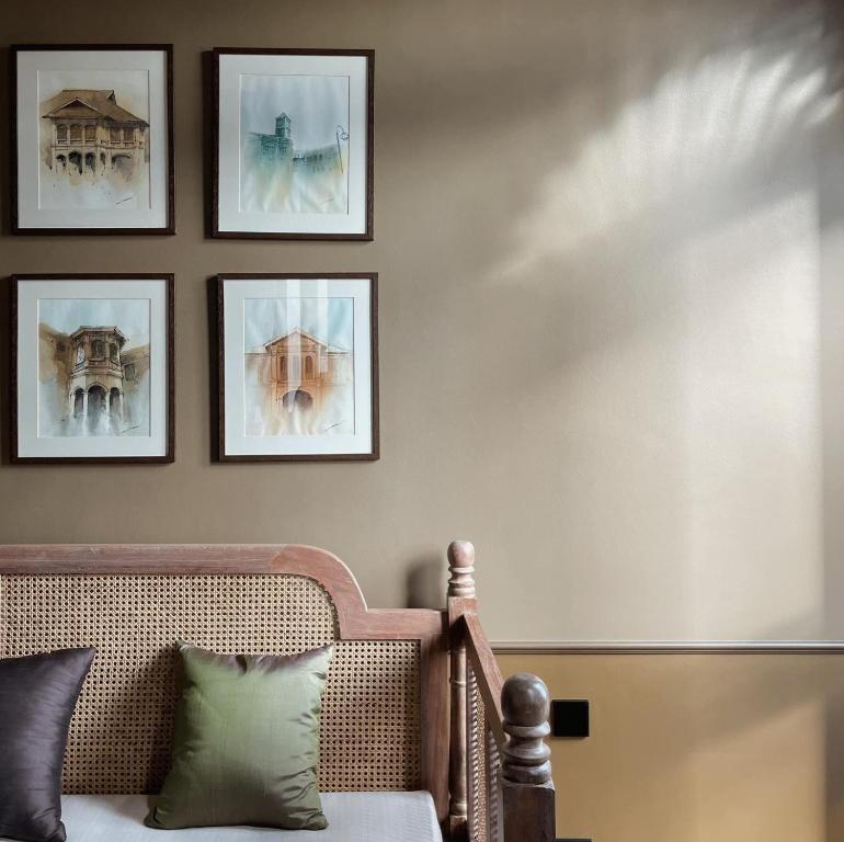uma sala de estar com um sofá e quadros na parede em Hotel Verdigris em Cidade Phuket