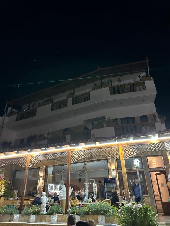 un restaurante con gente sentada fuera por la noche en Costas Inn, en Spílion