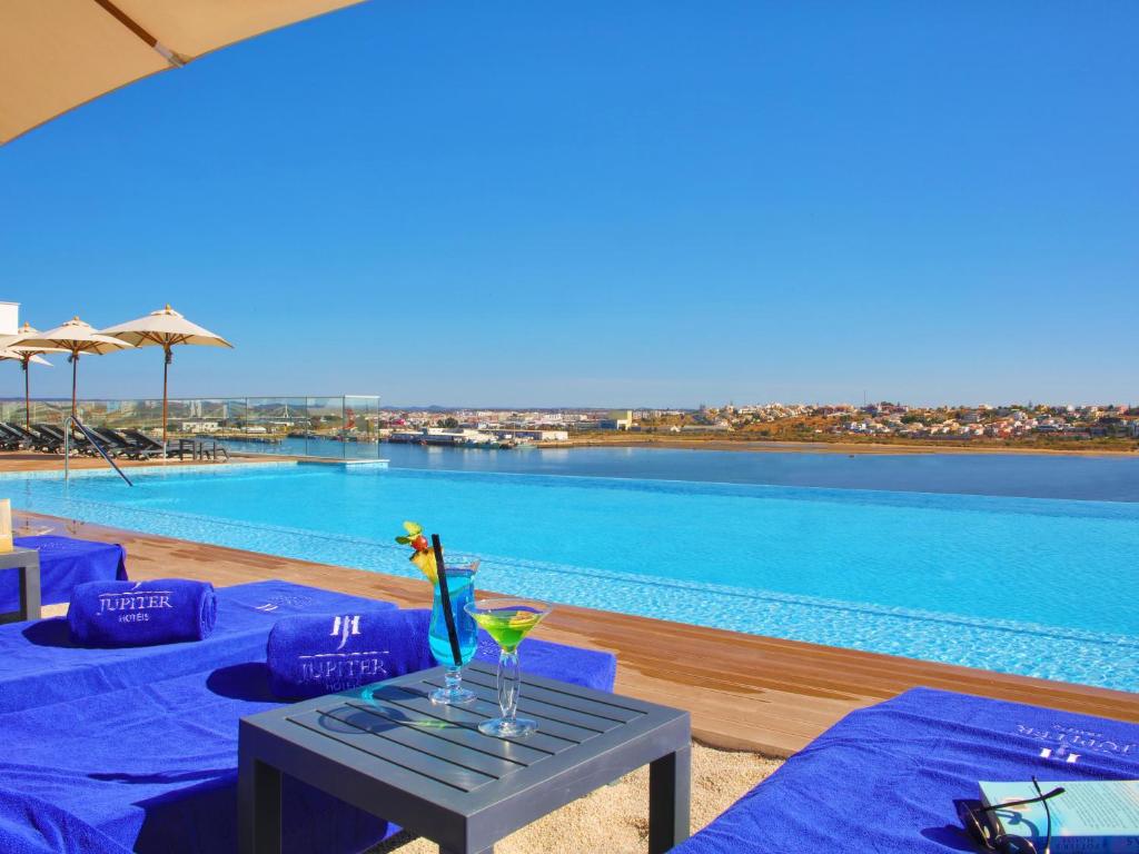 a pool with a table with a drink on it at Jupiter Marina Hotel - Couples & Spa in Portimão