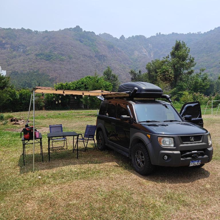 una camioneta negra estacionada en un campo con una mesa y sillas en Mini Camper Honda Element, en Guatemala