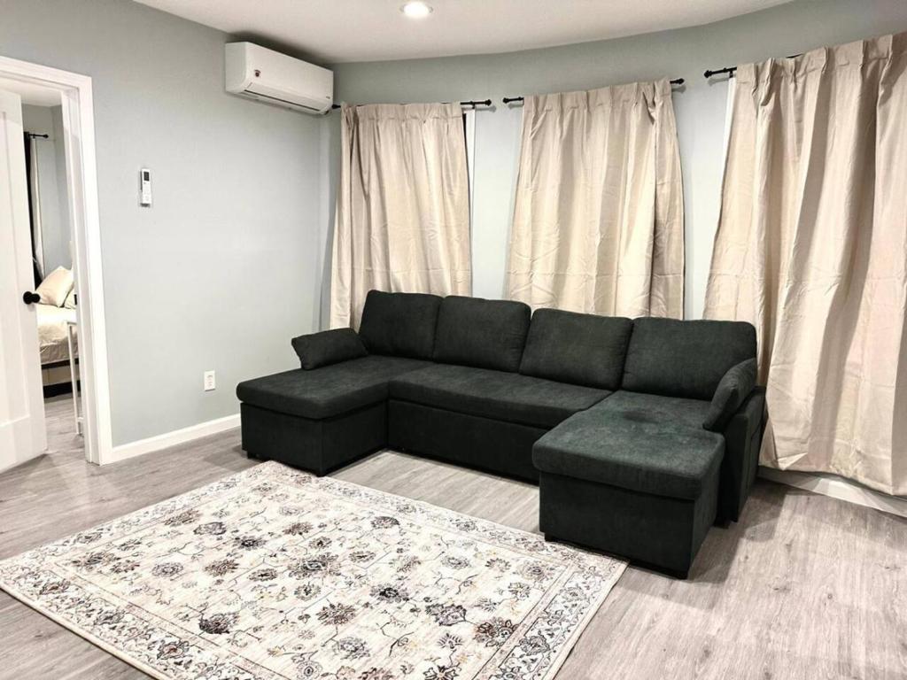 a living room with a black couch and a rug at Modern 3-Bdrm Apt in Black Rock in Bridgeport