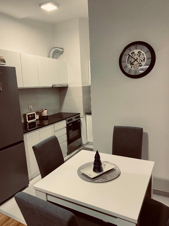 una cucina con tavolo, sedie e orologio sul muro di Apartman Zaga a Loznica