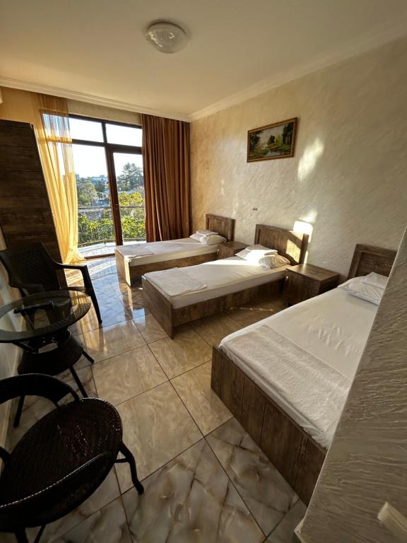 Habitación de hotel con 2 camas, mesa y sillas en Отель «JIMA” en Kobuleti