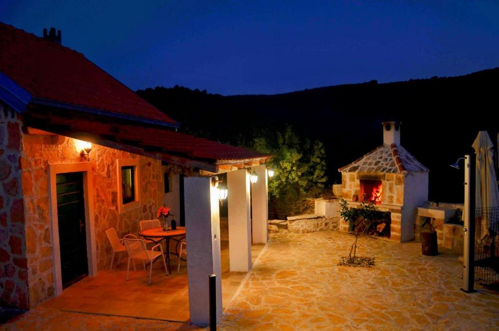 - une terrasse avec une table et une maison la nuit dans l'établissement STONE HOUSE ANA, à Škrip