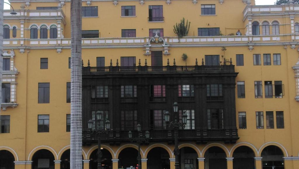 ein großes gelbes Gebäude mit Balkon in der Unterkunft Hostal President in Lima