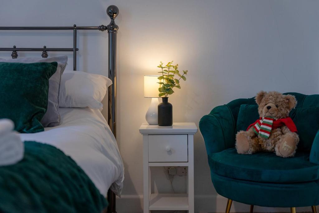 a teddy bear sitting in a chair next to a bed at Kirkmoor Cottage - Cosy home central Clitheroe in Clitheroe