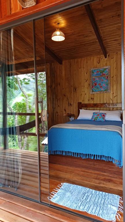 a bed in a room with a glass wall at Pousada Aconchego do Caboclo in Sapucaí-Mirim