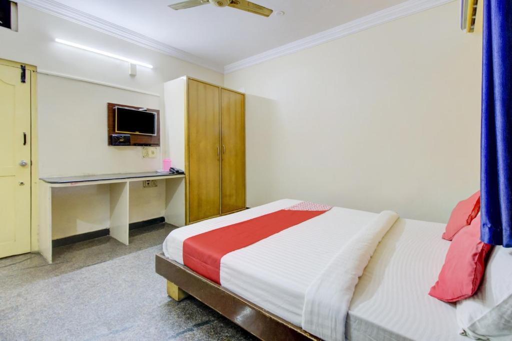 a bedroom with a bed and a desk and a television at OYO Hotel Vijay Residency in Bangalore